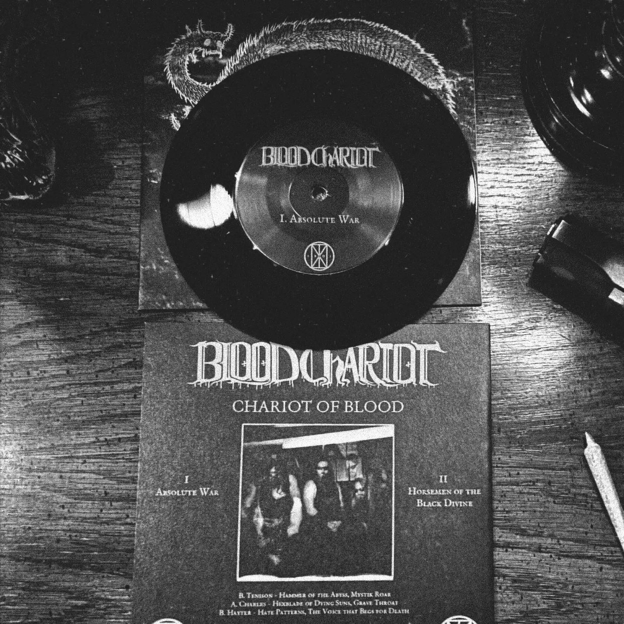 Blood Chariot, Chariot of Blood, 7-inch vinyl on a wooden table: the black record on its dragon-illustrated sleeve above the printed insert listing Absolute War and Horsemen of the Black Divine
